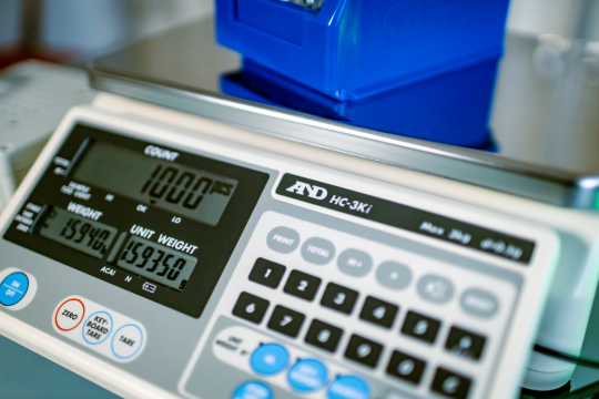 A&D HC-i Zählwaage mit Edelstahl-Wägeplatte auf hellem Arbeitstisch, beleuchtetes Display in Nahaufnahme