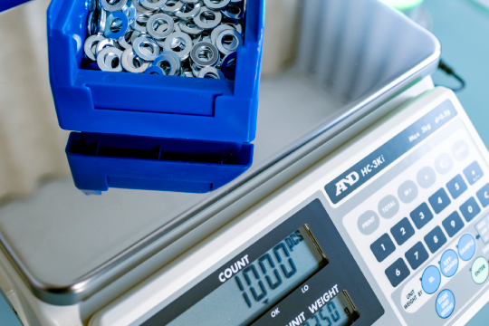 Seitenansicht der A&D HC-i Zählwaage auf Werkbank mit Hintergrund aus Lagerregalen